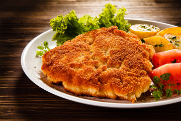 Fried pork chop with potatoes on wooden table