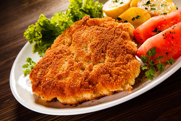 Fried pork chop with potatoes on wooden table
