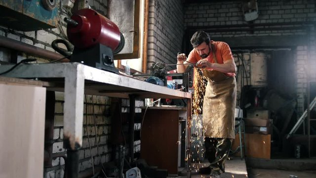 Worker in workshop processing metal details