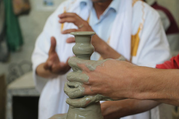 Human's hands are creating a clay jar