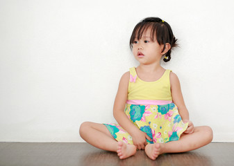 Portrait of asian child girl in swimming suit sitting on the floor and looking out.