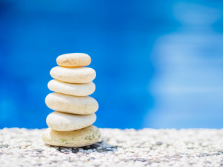 Balance Stones stacked to pyramid in the soft blue water background to Spa ideas design or freedom and stability concept on rocks.
