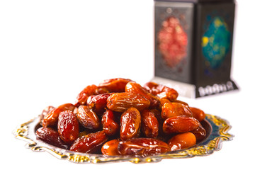 Beautiful a shining Fanus lantern and dried dates on a silver tray isolation on white background. The Muslim feast of the holy month of Ramadan Kareem. Free space for your text