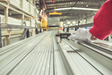 closeup of inspector checking finished pieces of aluminium alloy by using vernier caliper.