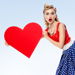 smiling woman holding heart symbol, dressed in pin-up style