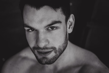 Portrait of young attractive man with muscular strong black beard, piercing sexy look in the studio posing