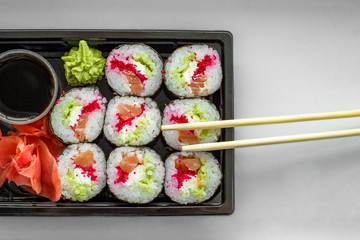 The plate of sushi with soy sauce, wasabi and chopsticks