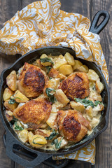 Roast chicken, potatoes and spinach with creamy sauce in a frying pan