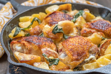 Roast chicken, potatoes and spinach with creamy sauce in a frying pan