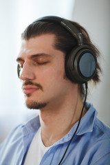 Music in his mind. Portrait of young man wearing headphones and closed eyes