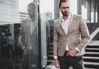 portrait of sexy handsome fashion male model man dressed in elegant beige checkered suit .posing on the street background