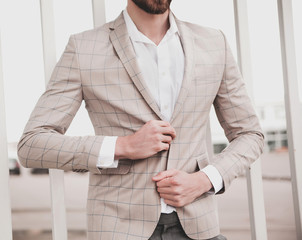 portrait of sexy handsome fashion male model man dressed in elegant beige checkered suit .posing on...