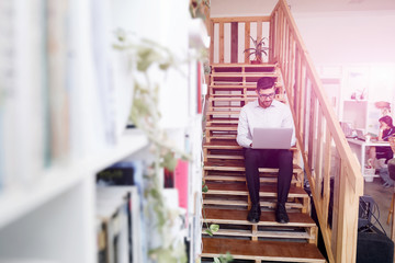 Portrait of young man sitting at the stairs in office