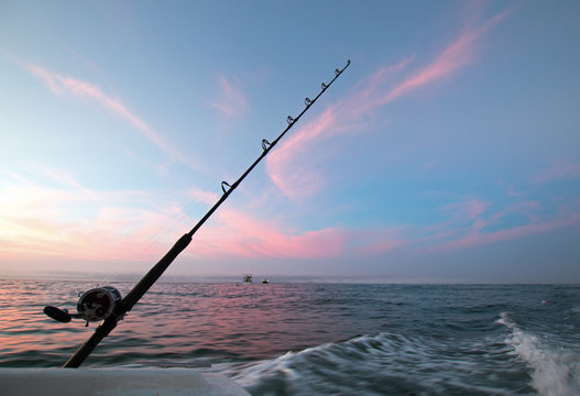 Fishing rod on charter fishing boat against pink sunrise sky on the Sea of Cortes in Baja Mexico BCS