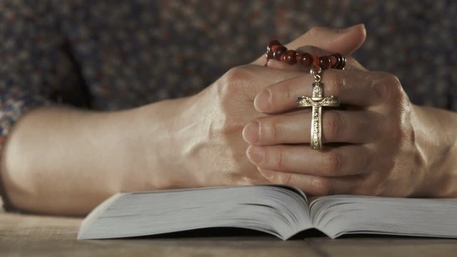 Woman praying with her bible on wooden table