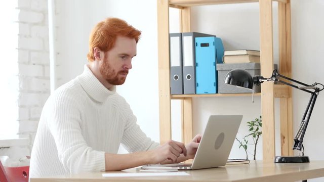 Man with Red Hairs Typing On Laptop in Office