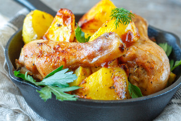 Baked potatoes with chicken in a cast-iron frying pan.