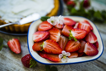Fresh strawberries and delicious sponge cake on a wooden background.