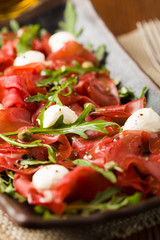 Beef carpaccio served with balls of mozzarella cheese, arugula and capers.