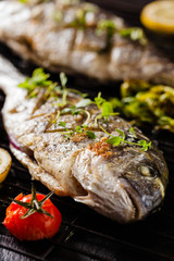 Grilled whole fish, served with roasted vegetables and lemon.