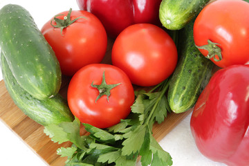 tomatoes, peppers ,cucumbers and parsley on a cutting Board