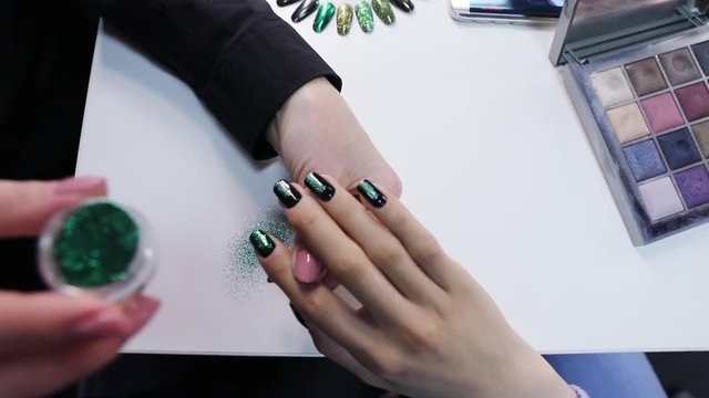 Manicurist making fashion nailart.  Woman Applying Green Glitter Nail Polish.