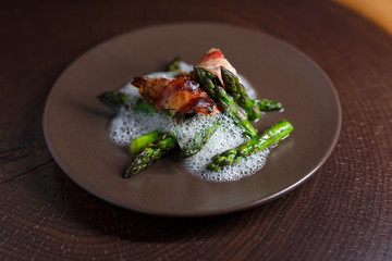 Spargel mit Huhn im Speckmantel auf braunem Teller