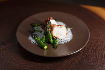 Spargel mit Huhn im Speckmantel auf braunem Teller