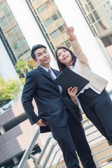 The businessman and the businesswoman talking about business project in downtown with building background