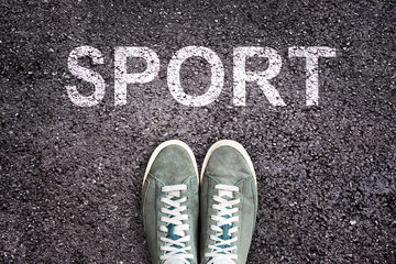 Word sport written on asphalt road with sneakers shoes, sport concept