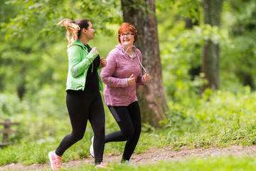 Mother and daughter wearing sportswear and running in forest at mountain
