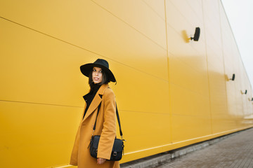 Fashionable girl at yellow wall