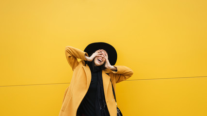 Stylish cheerful woman at yellow wall