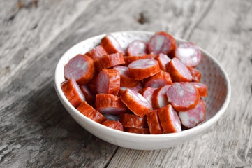 Smoked sausages in a plate on a wooden background. Food Photo