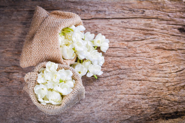 Fototapeta na wymiar Jasmine flower in burlap bag on old wood background,select focus