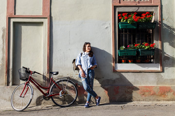 Fototapeta premium Portrait of beautiful young woman with bicycle in old town.