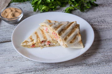 shawarma in thin pita bread with chicken and vegetables on a plate