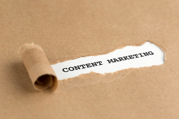 The text CONTENT MARKETING appearing behind torn brown paper