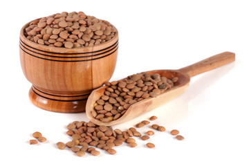 Lentils in a wooden bowl with a scoop isolated on a white background