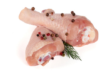 Two raw chicken drumsticks with a sprig of dill and peppercorns isolated on white background