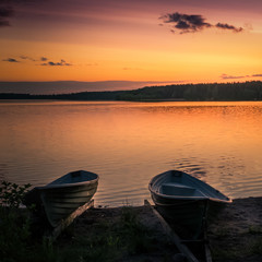 Landscape with lake, boats and sunset at summer evening in Finland