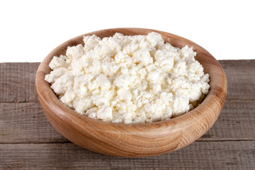 Cottage cheese in a wooden bowl on board with white background