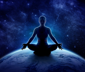 Yoga woman on the world. Meditation girl sitting in lotus pose on planet earth and star in dark...