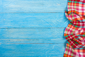 Red checkered tablecloth on a blue wooden table with copy space for your text. Top view