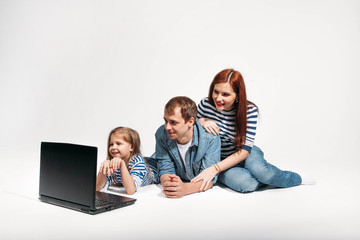 Happy family Father, mother and child lying on the floor with laptop on white background isolated
