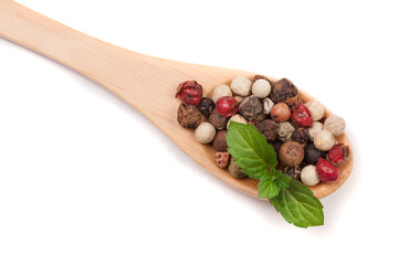 Mixture of peppers hot, red, black, white and green pepper in a wooden spoon isolated on white background. Top view