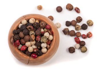 Mixture of peppers hot, red, black, white and green pepper in a wooden bowl isolated on white background. Top view