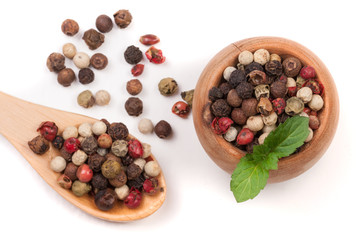 Mixture of peppers hot, red, black, white and green pepper in a wooden bowl and spoon isolated on white background