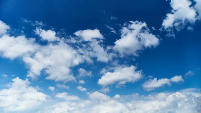 Time lapse video of white cumulus and fleecy clouds morphing on blue sky