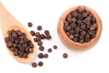 Black peppercorn in a wooden bowl and spoon isolated on white background. Top view